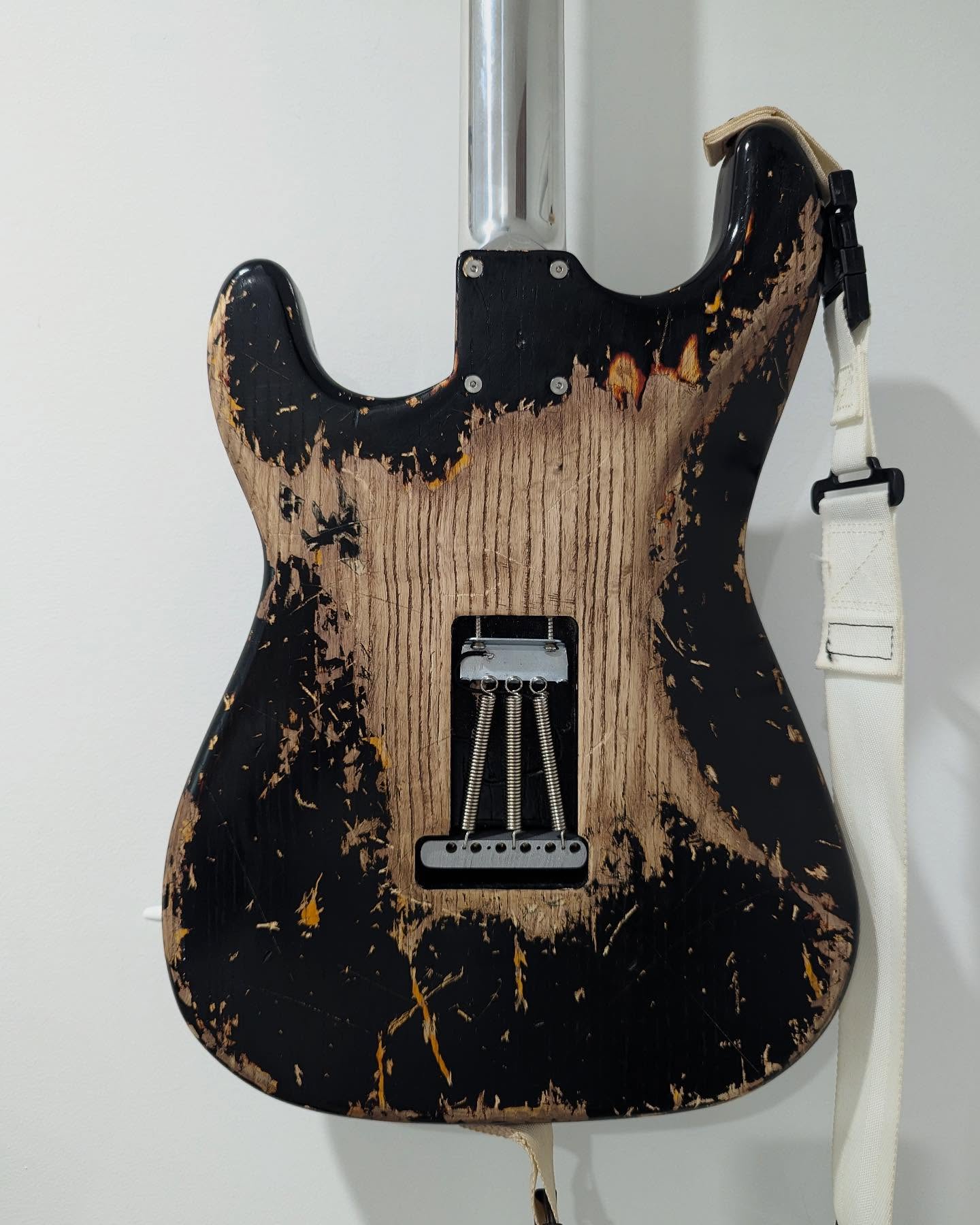 The DB-1’s heavily aged black body, exposed tremolo springs and aluminum neck, viewed from the back
